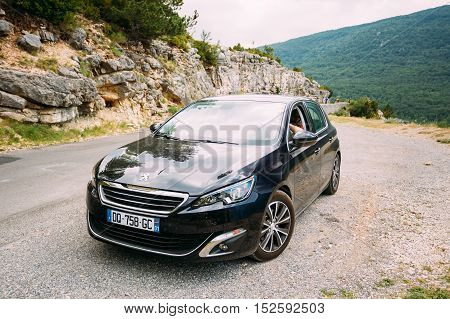Verdon, France - June 29, 2015: Black colour Peugeot 308 5-door car on background of French mountain nature landscape. The Peugeot 308 is a small family car produced by French car manufacturer Peugeot