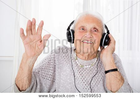 Portrait Of Happy Senior Woman Enjoying Music With Headphone At Home
