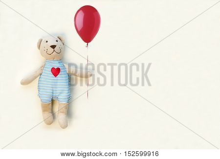 Teddy bear with red balloon on a white background