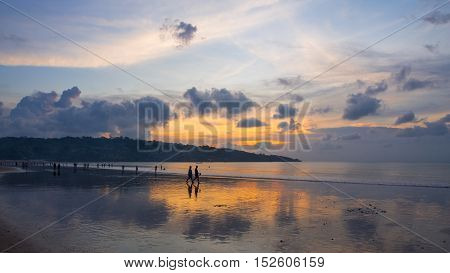 Holiday makers at Jimbaran Beach in Bali Indonesia at sunset.