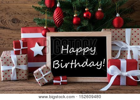 Colorful Christmas Card For Seasons Greetings. Christmas Tree With Red Balls. Gifts Or Presents In The Front Of Wooden Background. Chalkboard With English Text Happy Birthday