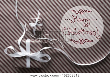Two Gifts Or Presents With White Ribbon. Brown Striped Wrapping Paper. Christmas Or Greeting Card For Seasons Greetings. Red English Text Merry Christmas