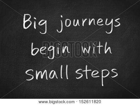 big journeys begin with small steps concept text on blackboard background