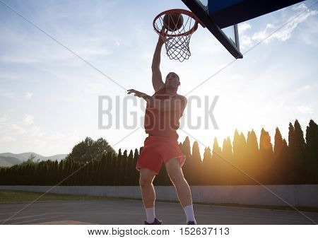 Young Man Jumping And Making A Fantastic Slam Dunk Playing Streetball, Basketball. Urban Authentic.
