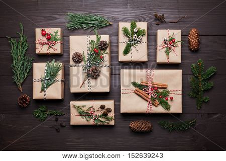 Gift or present box wrapped in kraft paper with christmas decoration on rustic wooden table from above. Flat lay style.