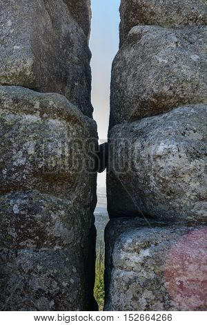 Small stone is stuck between gaps of two huge boulders