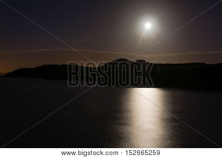 Hunter's moon over sea at Sand Point. Full moon reflected in water of Bristol Channel at high tide in Somerset England UK with clouds and coast