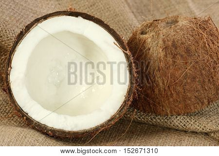 fresh coconut cut in half on a hessian background