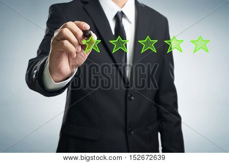Review increase rating performance and classification concept. Businessman draw five green stars to increase rating of his company blank background.