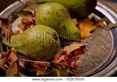 Rural vintage autumn ripe green pears, yellow leaves on a silver tray, natural fall style decorations. Natural plenteous fruits vintage background.