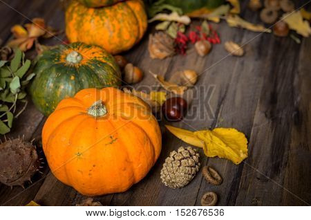 Autumn decorative pumpkins, fall leaves on a rustic wooden background, natural fall style decorations. Natural plenteous border background vintage mock up.