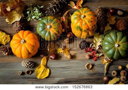 Autumn decorative pumpkins, fall leaves on a rustic wooden background, natural fall style decorations. Natural plenteous border background vintage mock up. Top view point.