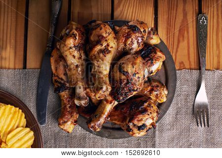 Roasted chicken legs with knife and fork on a wooden background