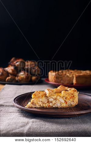 Piece of a chicken meat pie on plate on a black wooden background. Vertical shot. Dark photo