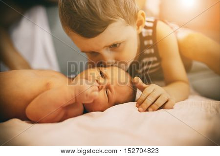 Brother kissing sweet little cute newborn sister