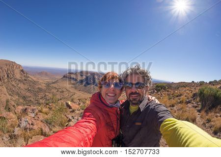 Adult couple taking selfie on panoramic viewpoint in Marakele National Park travel destination in South Africa. Concept of adventure and traveling people. Fisheye view in backlight.