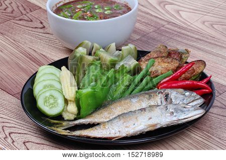 Close up ready side dish served  for Thai spicy sour dip   as deep fired mackarels,boiled long-eggplant,lentils,winged bean ,red hot chili pepper and sliced cucumber on wood.  Selective focus.