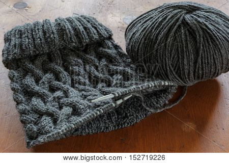 The process of knitting a hat with extensive cabling.