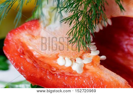 The fruit of red bell pepper cut lengthwise visible core of fruit and seeds. Presents closeup.