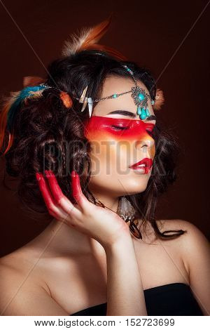 Beautiful squaw in ethnic jewelry . Close up portrait. Native american costume. Portrait of a woman with a painted face. Creative makeup and bright style.
