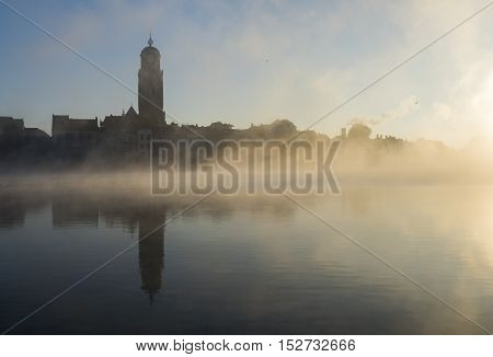 Deventer at the IJssel in the morning during sunrise with the Great Church or Lebuinuskerk and fog in the province Overijssel The Netherlands.