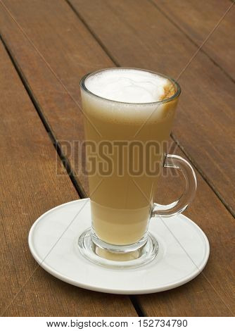 Transparetn glass of hot latte on the wooden table