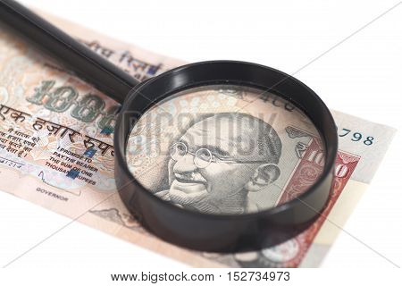 Indian Currency Rupee Note with magnifying glass isolated on white background