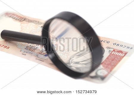 Indian Currency Rupee Note with magnifying glass isolated on white background