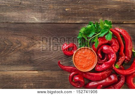 Homemade sauce and red hot chili peppers and celery on rustic wooden background. Top view.