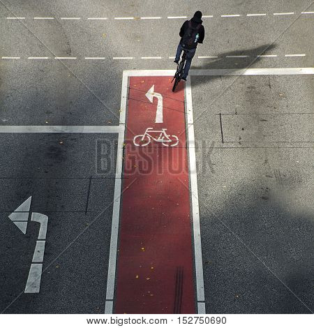 anonymous cyclist from behind on a bike lane with symbol and arrow driving in the wrong direction on the asphalt road concept for driving school and traffic safety