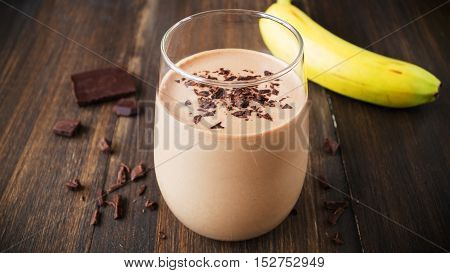 Chocolate banana smoothie in glass on wooden background selective focus horizontal toned