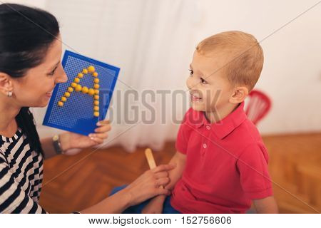 Little boy during lesson with his speech therapist. Learning through fun and play