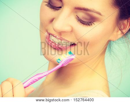 Woman brushing cleaning teeth. Girl with toothbrush. Oral hygiene. Bright green background