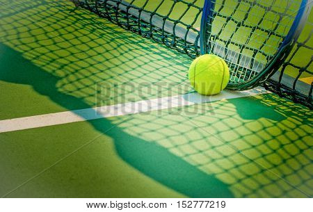 Tennis ball on green tennis court with racket