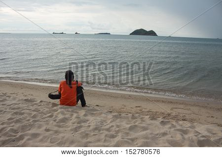 young woman sitting on the beach and looks at sea in relaxing holiday