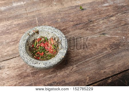 chilli pepper in stone mortar on the wooden table paste spicy herb ingredient food Thailand ancient style. Image Top view