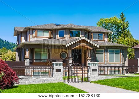 Luxury residential house with iron fence and green lawn in front
