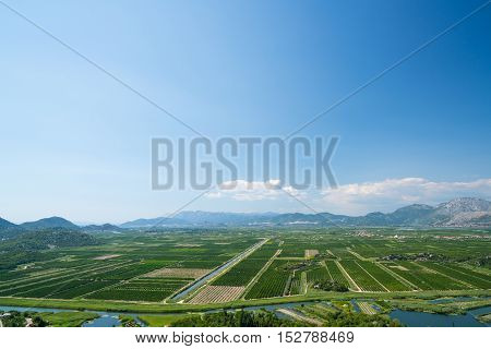 aerial view of beautiful Neretva valley in southern Croatia with numerous crop fields and hills in distance.
