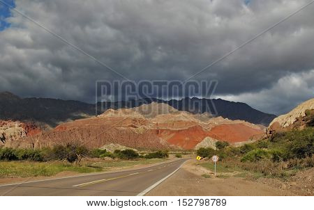 Road leading to vibrant colored rocks under a dramatic sky
