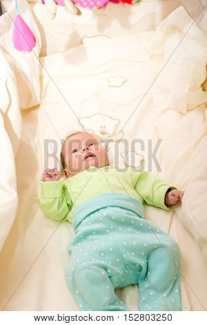 baby girl lying and playing in her crib