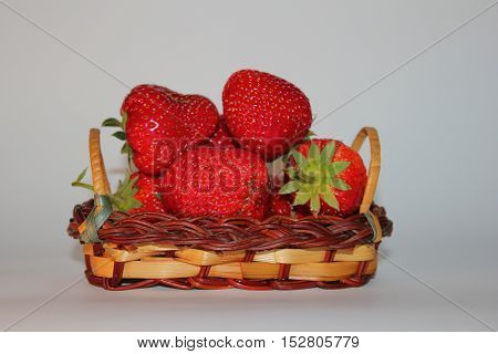 few ripe red strawberries on a white background in the basket