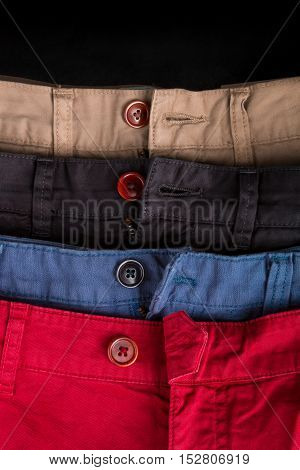 Fragment Of Four Cotton Twill Pants Red, Blue, Black, Beige With Open Buttons. Close Up.