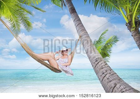view of nice young lady swinging  in hummock on tropical beach