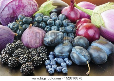 Blue and purple food. Berries fruits and vegetables on a black background.
