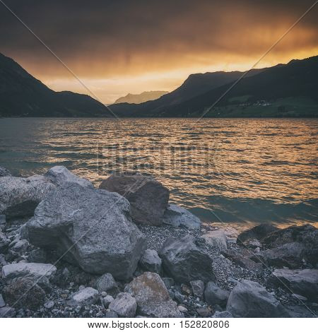 Beautiful view of the lake Resia. Dramatic sky and colorful sunset. Alps, Italy, Europe, toned like Instagram filter