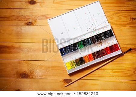 Watercolor aquarell paints in box with brush on wooden background