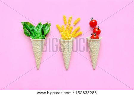 Italian pasta ingredients concept spiral macaroni tomatos and basil in waffel cones cute minimal photo flat lay