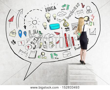 Rear view of blond woman drawing business idea sketch on concrete wall while standing on stairs. Concept of idea development