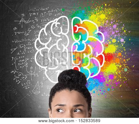 Close up of African American woman's head with large brain drawing. One hemisphere is colored. The second is surrounded by formulas. Concept of logic and creativity
