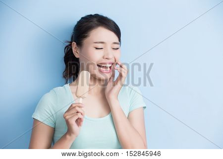 woman have sensitive teeth with ice isolatd on blue background asian